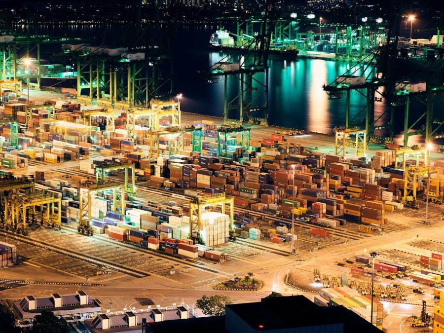 Illuminated container terminal with stacked shipping containers and cargo cranes at night