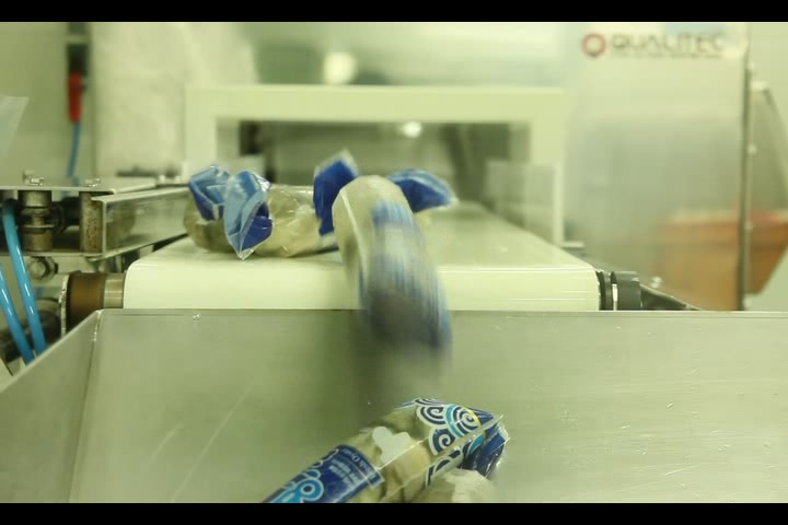 Oyster products in blue packaging moving along a conveyor belt in a seafood processing facility.
